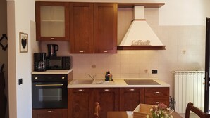 Una cocina compacta con armarios de madera, horno empotrado, cafetera y lavamanos.