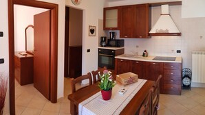 Cocina compacta con armarios de madera, cafetera, microondas y un lavamanos.