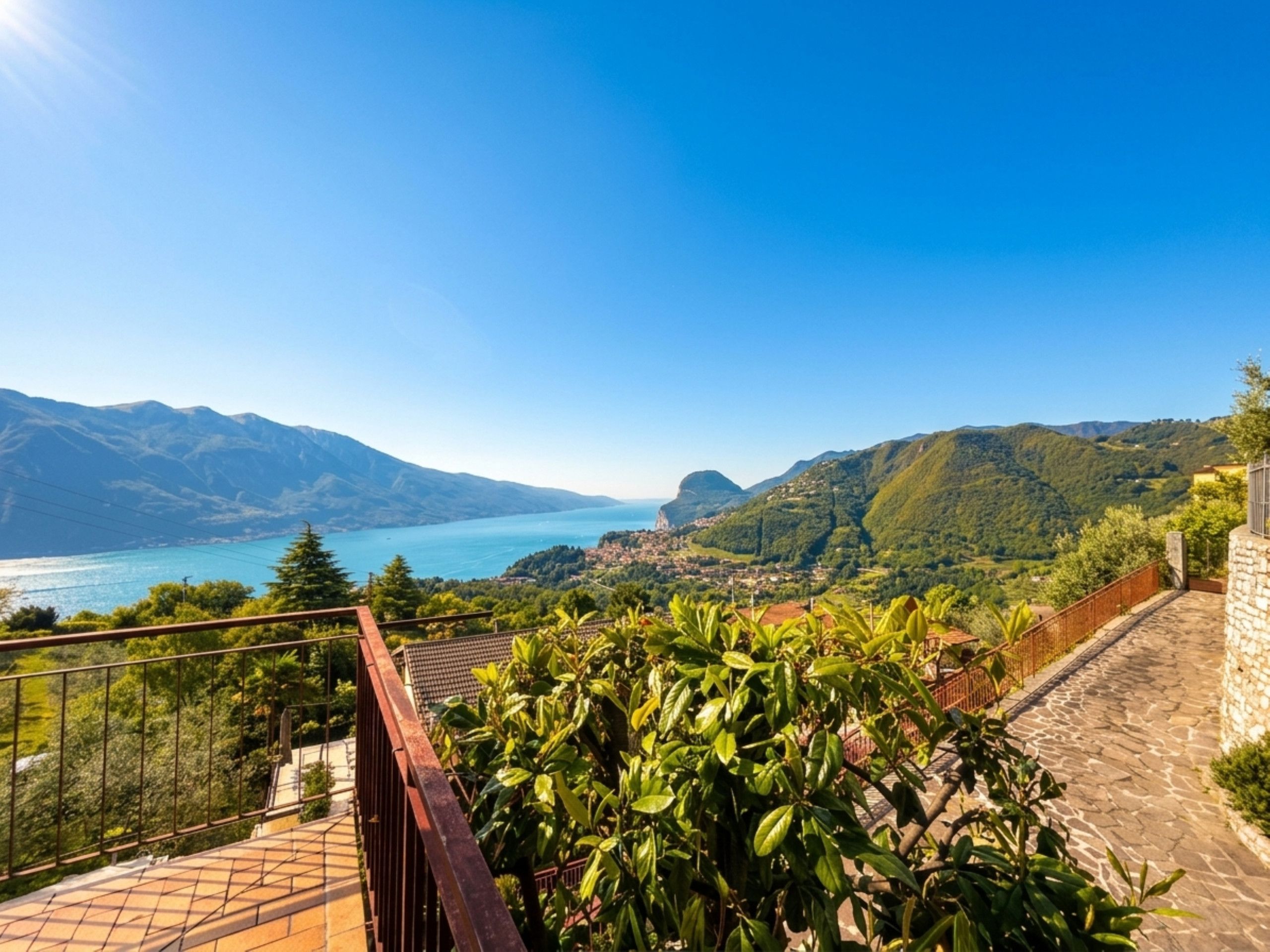 A balcony with a view of a lake, mountains, and a town in the distance.