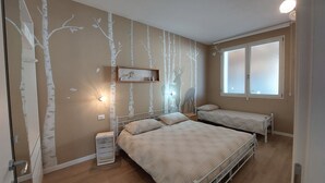 Una camera da letto con due letti, un comodino, uno scaffale con un quadro e una finestra.