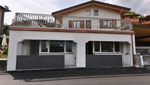Un edificio moderno a due piani con un balcone, ampie finestre e un garage.
