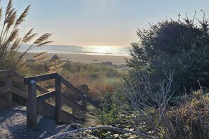 A wooden staircase leading to a beach with a view of the ocean and coastal vegetation. - Friends & Family Seaside Retreat, Walk to Beach! (Gold Beach)