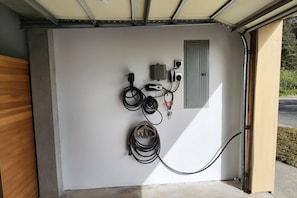 A garage with a white wall, electrical outlets, and a door. - Friends & Family Seaside Retreat, Walk to Beach! (Gold Beach)