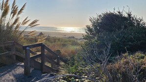 Une porte en bois qui mène à une plage offrant une vue sur l’océan.