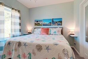 A bedroom with a bed, two bedside tables, a window with curtains, and three wall-mounted pictures. - Friends & Family Seaside Retreat, Walk to Beach! (Gold Beach)