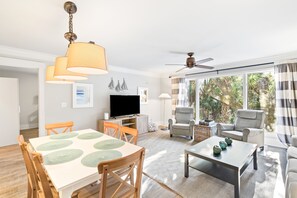 Una sala de estar moderna con comedor, televisor de pantalla plana y ventilador de techo.