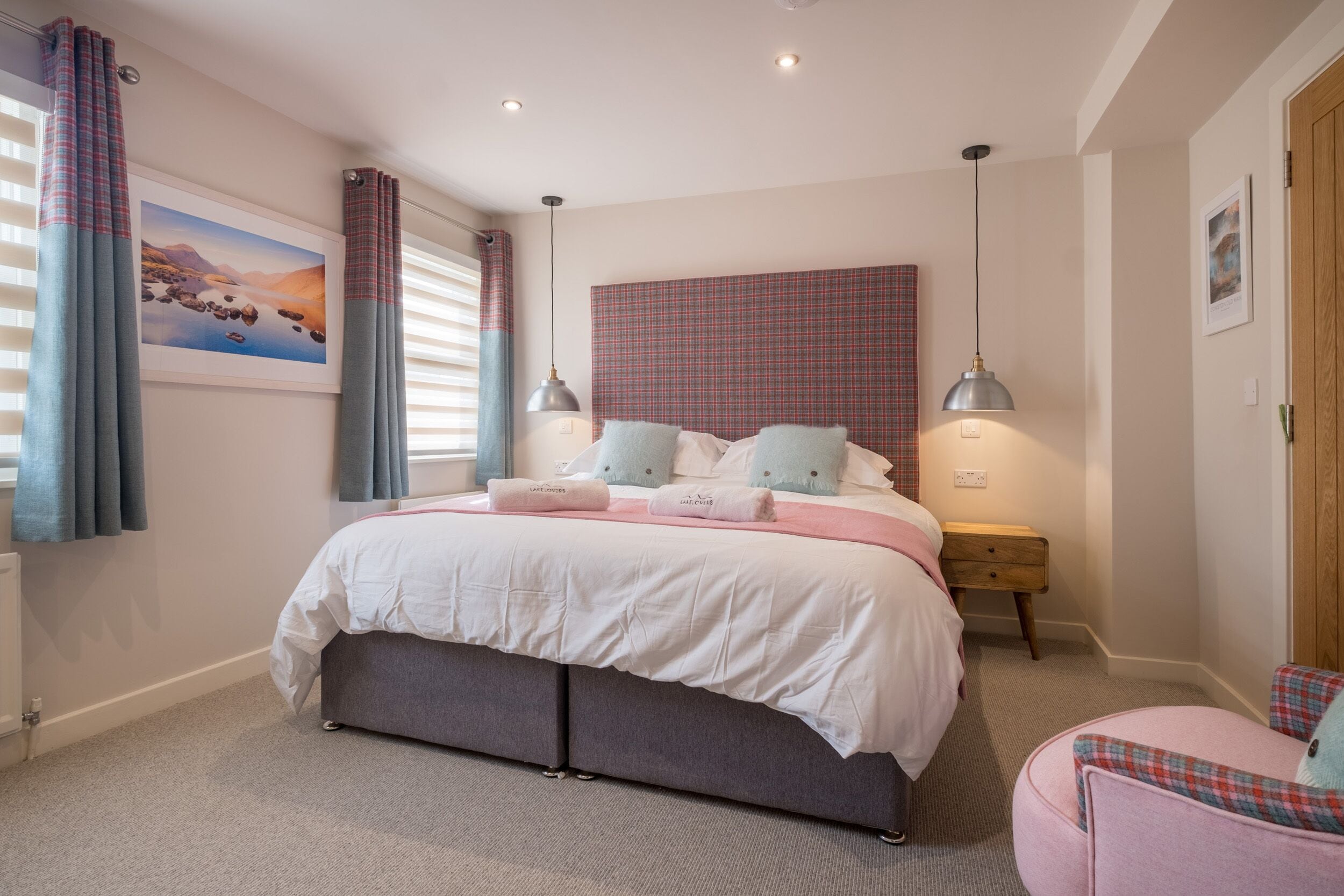 A bedroom with a bed, bedside tables, a nightstand, a chair, and a window with curtains.