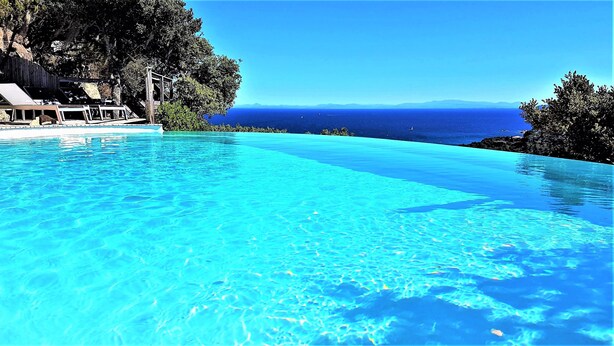 Ein klares, blaues Infinity-Pool mit Blick auf das Meer und ferne Berge.