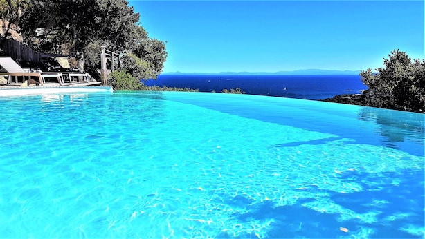 A clear blue infinity pool with a view of the ocean and distant mountains. - Apartment for 2 to 4 people with 1 bedroom. (Porto-Vecchio)