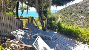 A wooden deck with lounge chairs overlooking a coastal landscape. - Apartment for 2 to 4 people with 1 bedroom. (Porto-Vecchio)