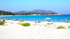 A beach with people sunbathing and swimming, a clear blue sky, and distant mountains. - Apartment for 2 to 4 people with 1 bedroom. (Porto-Vecchio)