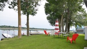 Un espace verdoyant avec un phare aux rayures rouges et blanches, des sièges en plein air et une vue sur l’eau.