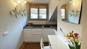 A compact kitchen with white cabinets, a sink, and a window with curtains. - Juniper House via Mazzini (Torino)