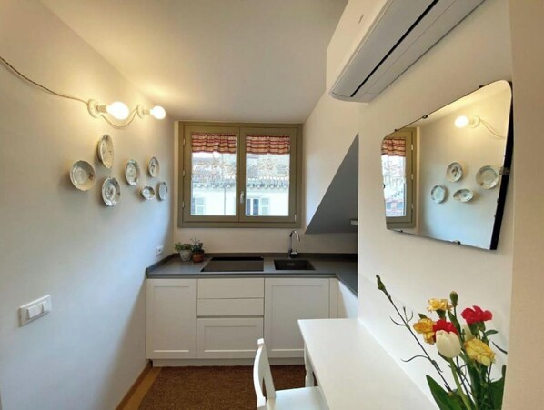A compact kitchen with white cabinets, a sink, and a window with curtains.