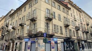 A multi-story building with balconies, a ground-floor shop, and closed shutters. - Juniper House via Mazzini (Torino)