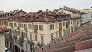 A row of terracotta-roofed buildings with uniform window designs, likely part of a historic district. - Juniper House via Mazzini (Torino)