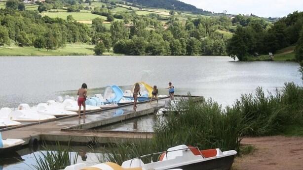 A lakeside dock with several boats and people near the water.