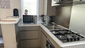 A compact kitchen with a gas stove, microwave, and sink.