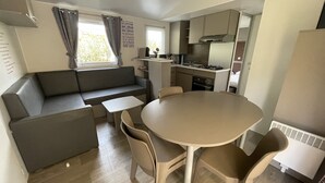 A compact kitchenette with a gas stove, oven, and sink. There is a gray sofa with a small table and chairs in the living area.