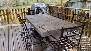 A wooden deck with a table and chairs, overlooking a green landscape.