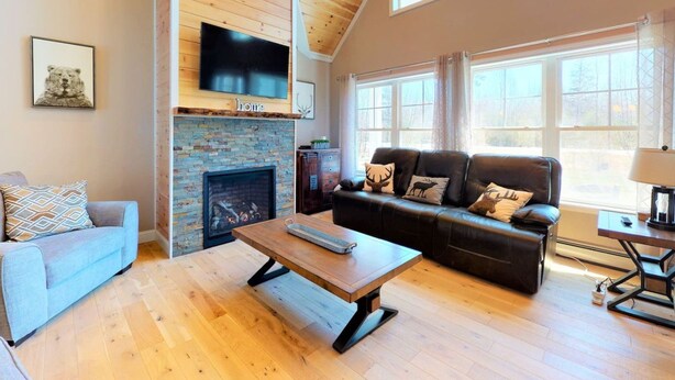 A living room with a fireplace, a sofa, a coffee table, and a television mounted on the wall. - Gorgeous Conway Home A/C, Hot Tub & Full Game Room (Conway)