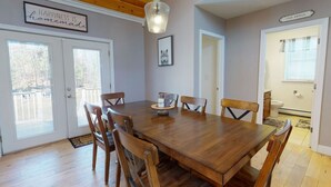 A dining area with a wooden table and chairs, a hanging light fixture, and a sign on the wall. - Gorgeous Conway Home A/C, Hot Tub & Full Game Room (Conway)