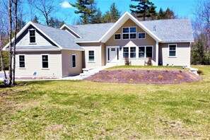 A two-story house with a front porch, a small garden, and a driveway.