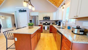 A modern kitchen with a central island, stainless steel appliances, and wooden cabinetry. - Gorgeous Conway Home A/C, Hot Tub & Full Game Room (Conway)