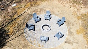 A circular outdoor seating area with six Adirondack chairs arranged around a central fire pit. - Gorgeous Conway Home A/C, Hot Tub & Full Game Room (Conway)