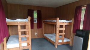 Ein Zimmer mit Etagenbetten, einem Kühlschrank und einem Fenster mit Vorhängen.