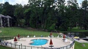 A pool area with a circular pool, lounge chairs, and umbrellas.