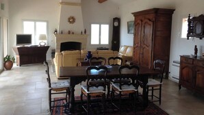 A spacious living room with a fireplace, a dining table with chairs, a sofa, and a television. - La Cadière, Villa 230m2 in a quiet area, superb panoramic view, infinity pool (La Cadière-d'Azur)