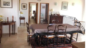 A dining area with a table set for four, wooden chairs, a patterned rug, and a staircase leading to an upper level. - La Cadière, Villa 230m2 in a quiet area, superb panoramic view, infinity pool (La Cadière-d'Azur)