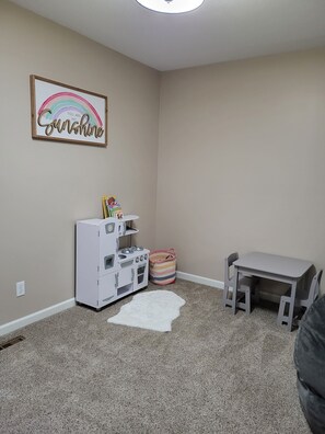 Quarto com cozinha compacta, uma mesinha e um espaço de recreação.