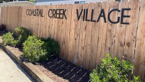 A wooden fence with "COASTAL CREEK VILLAGE" written on it.