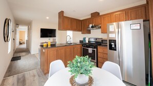 A modern kitchen with wooden cabinets, stainless steel appliances, and a dining area with a table and chairs.