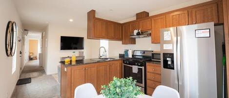 A modern kitchen with wooden cabinets, stainless steel appliances, and a dining area with a table and chairs.