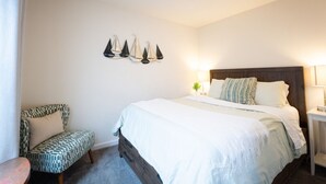 A bedroom with a bed, a patterned armchair, a nightstand, and wall-mounted decorative items.
