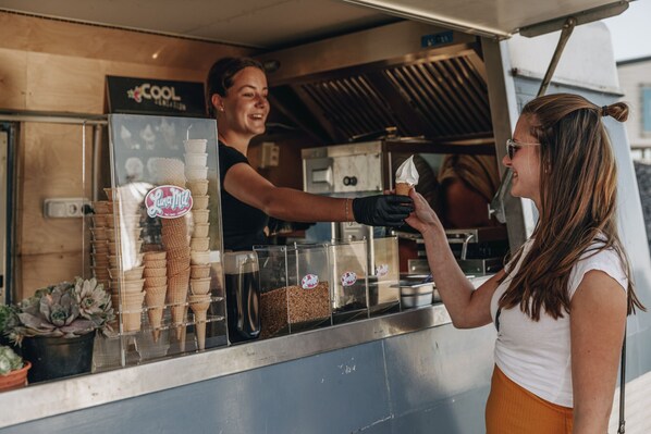 A food truck with a variety of ice cream cones and a sign that reads "COOL CREAMERY."