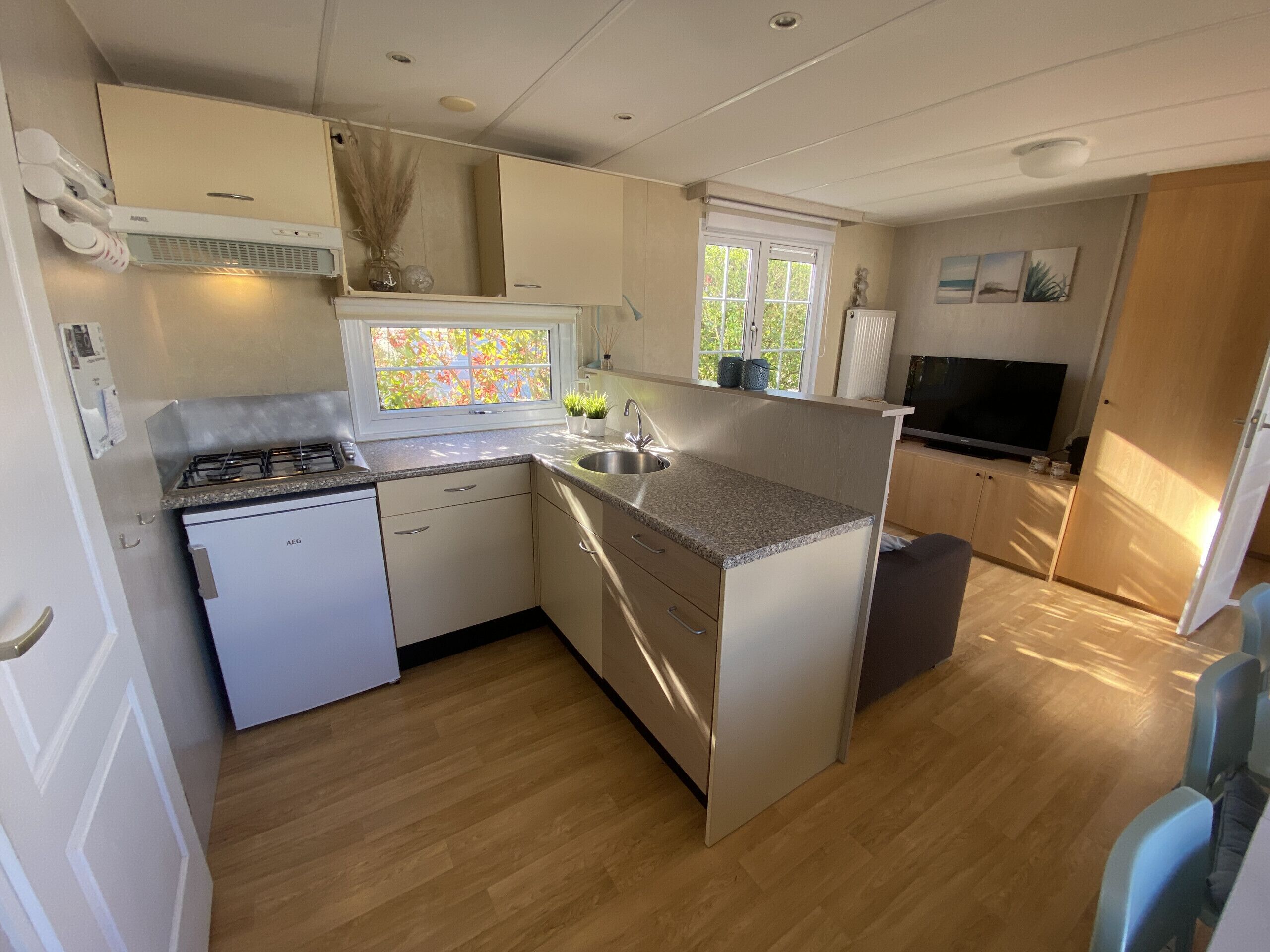 A compact kitchen with a gas stove, sink, and white cabinetry.