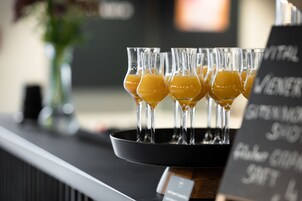 Uma área de bar com vários copos de suco de laranja em uma bandeja.