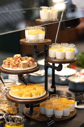 A multi-tiered dessert display with various types of cakes and puddings.