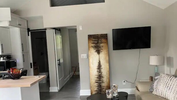 Un salon moderne avec un canapé, une table basse, un téléviseur à écran plat et un grand tableau abstrait.