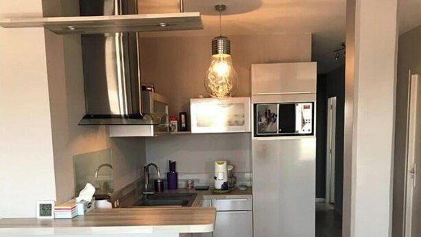 A modern kitchen with stainless steel appliances, a wooden countertop, and two black bar stools. - Apartment ST JEAN Centre Ville Wifi Balcony Parking (Saint-Jean-de-Monts)