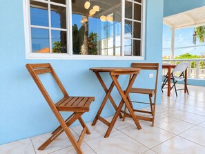A room with a blue wall, a window with white frames, and a table with chairs.