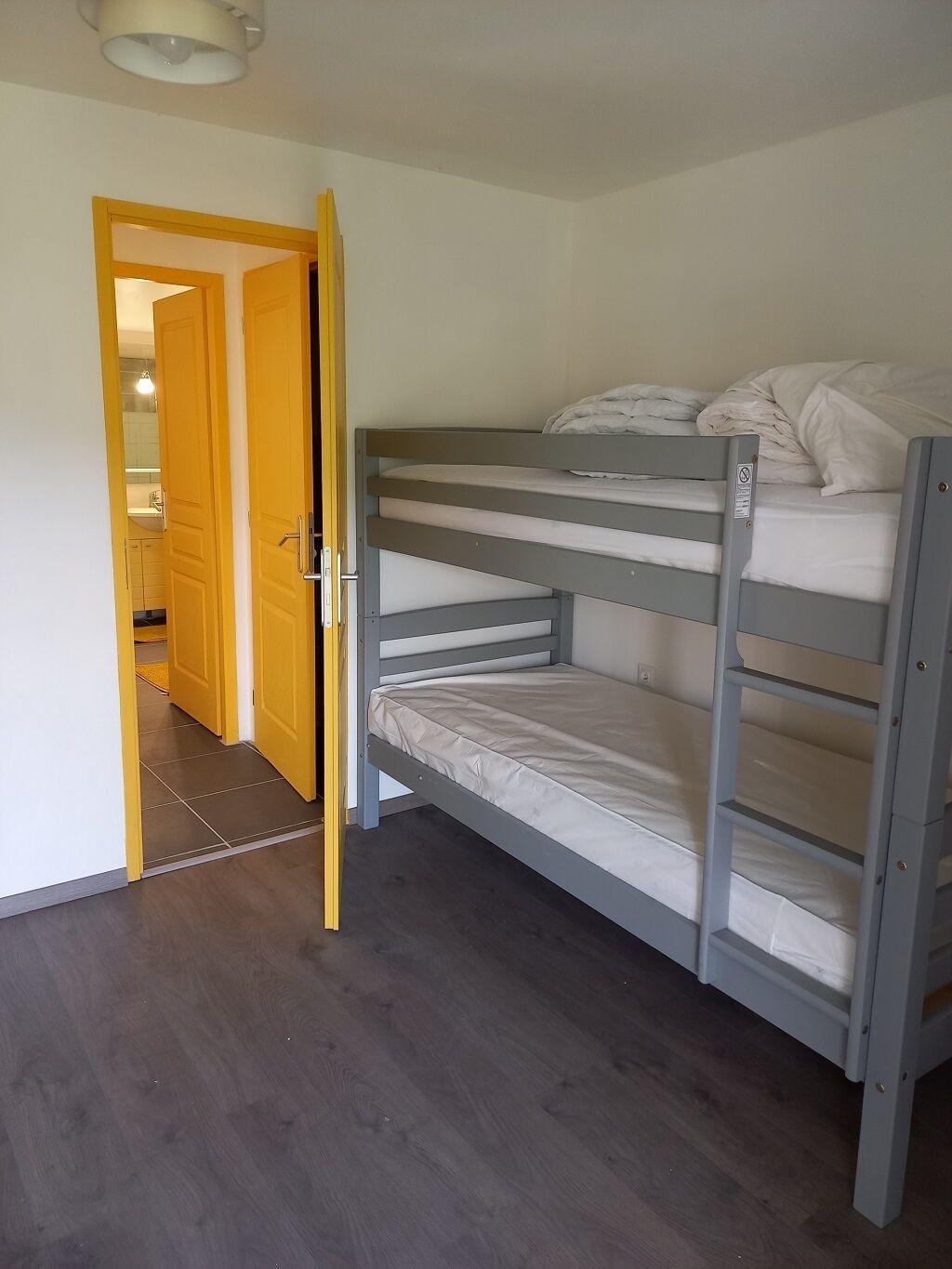 Habitación con literas y una puerta de madera que da a un baño.