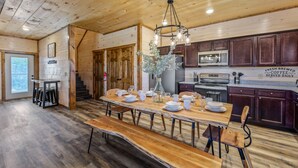 A spacious kitchen with wooden floors, a large dining table set for six, and a sign indicating fresh brewed coffee served daily. - Cabin with hot tub close to all the action! (Pigeon Forge)