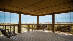 Een houten terras met een schommel, een bankje en uitzicht op het strand.