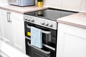 A kitchen with a built-in oven and microwave, stainless steel appliances, and white cabinetry.