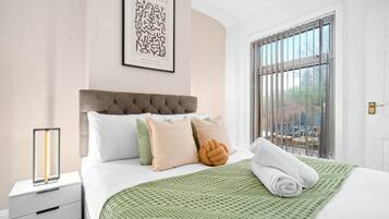 Ein ordentlich bezogenes Bett mit einer grün gemusterten Decke, einem Kopfteil und mehreren Kissen.